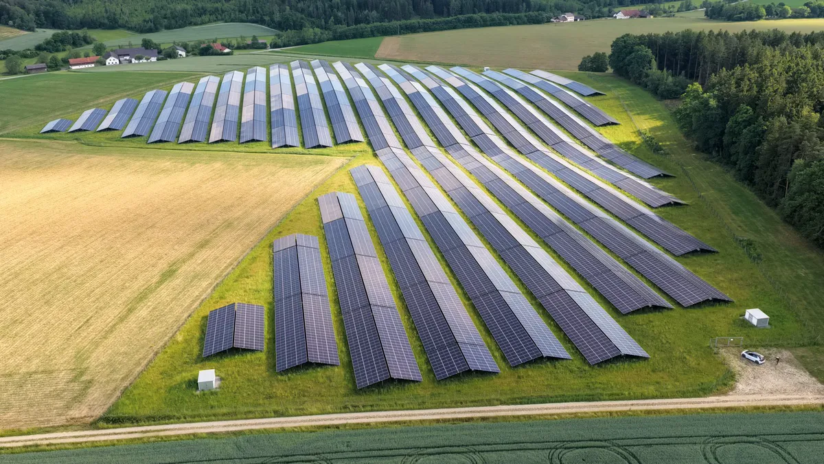 Luftaufnahme einer Photovoltaik-Freiflächenanlage in hügeligem Gelände