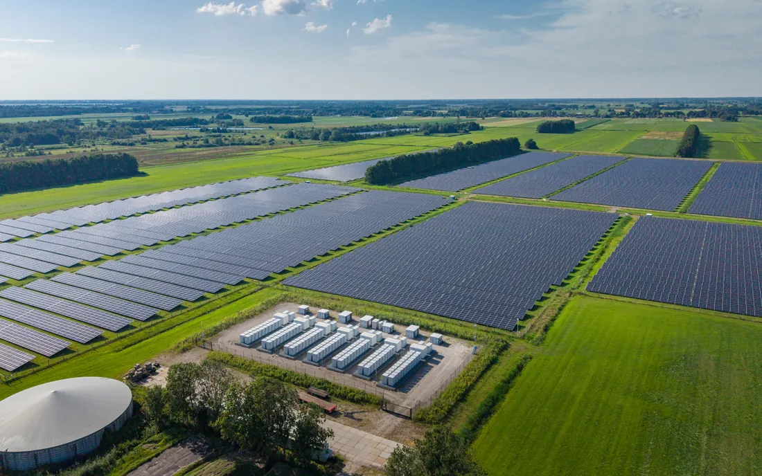 Luftbild einer Freiflächen-Photovoltaikanlage mit angeschlossenen Batteriespeicher-Containern